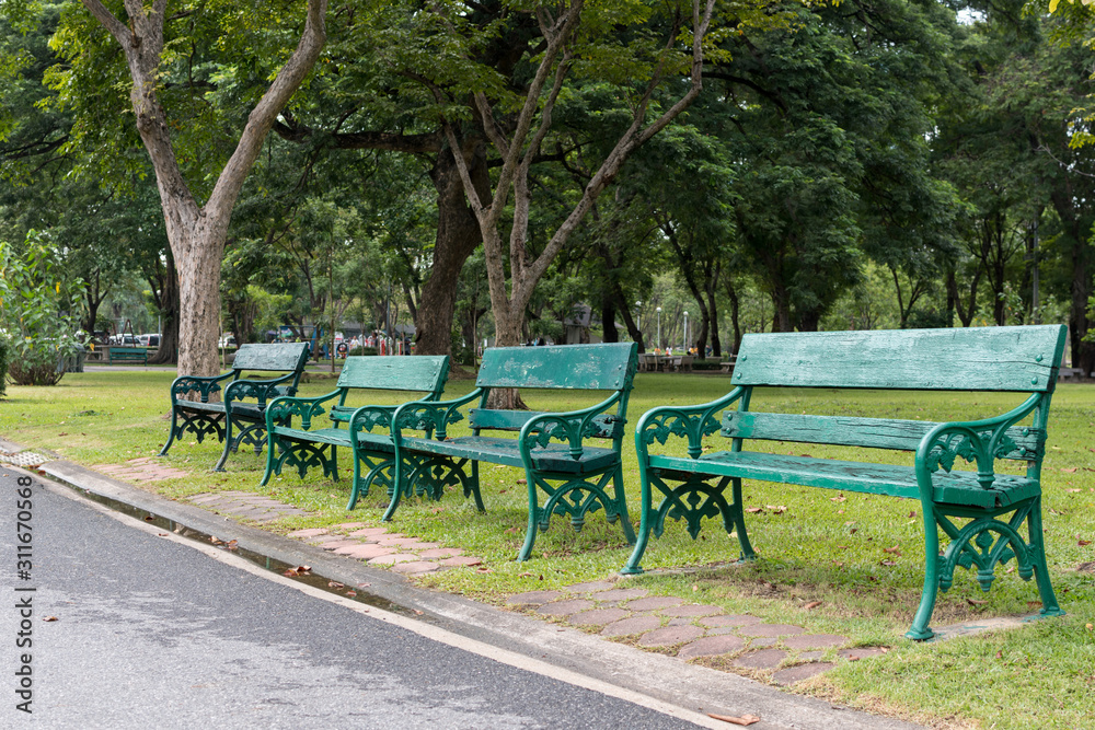 Old green wooden benches and footpath in the city park Old green wooden benches and footpath in the city park