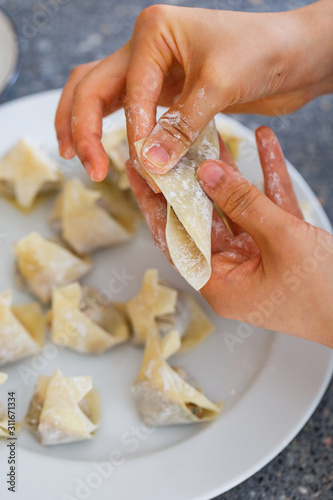 making a wonton by wrapping the wonton wrap over the filling