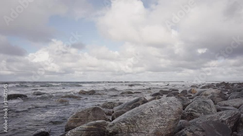 Small waves rolling in on a rocky beach with clouds