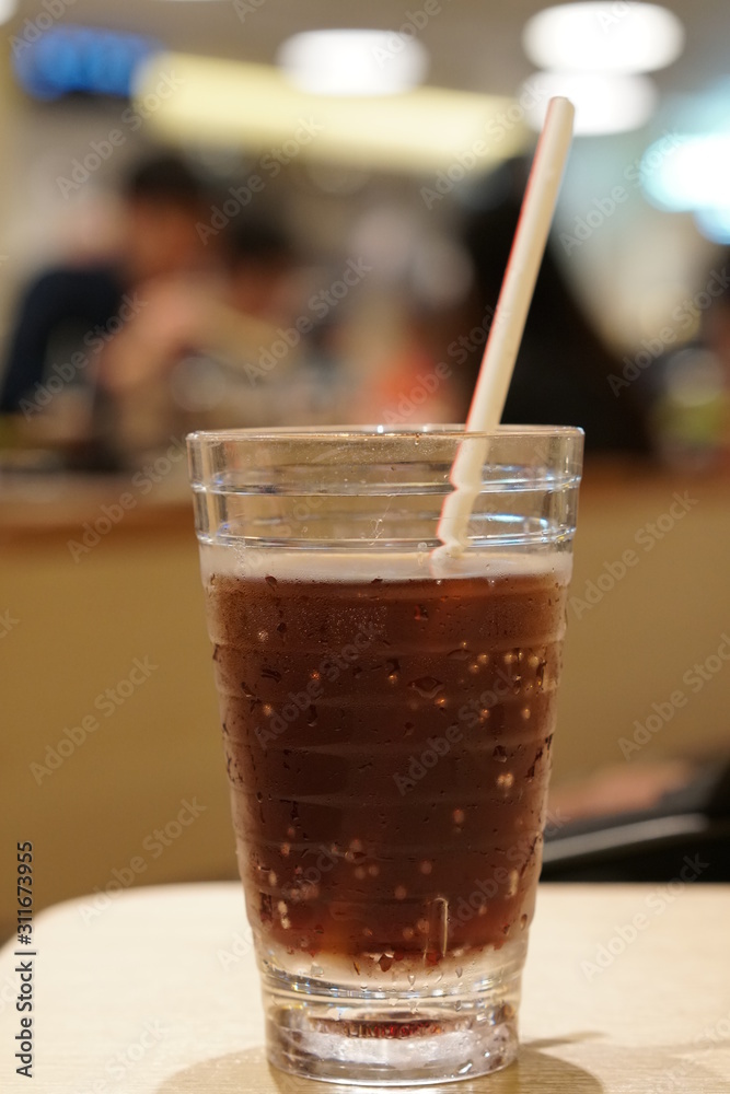The glass of cola with ice on the wooden table at restaurant. The glass of cola with ice on the wooden table at restaurant.