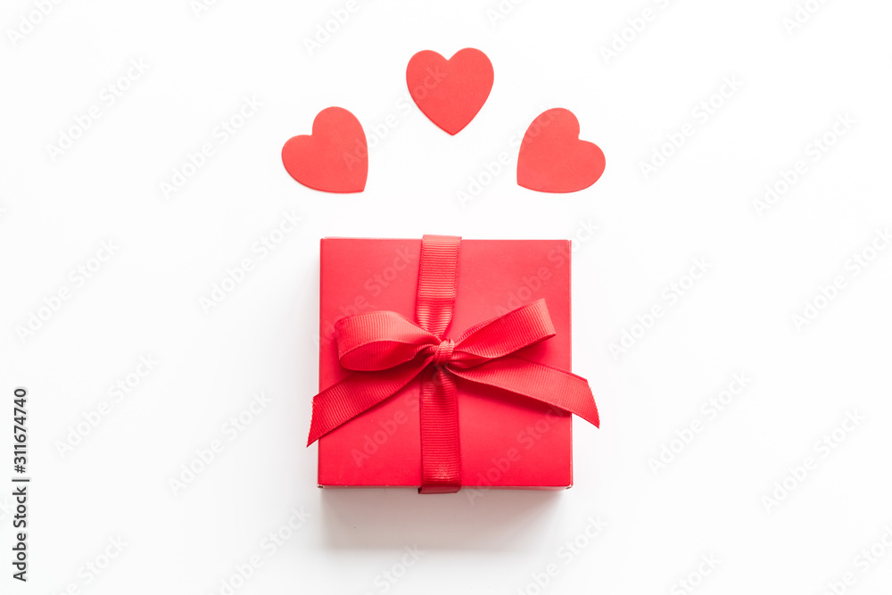 Gift to a sweetheart on Valentine's Day. Red present box near hearts on white background top-down copy space Gift to a sweetheart on Valentine's Day. Red present box near hearts on white background top-down copy space
