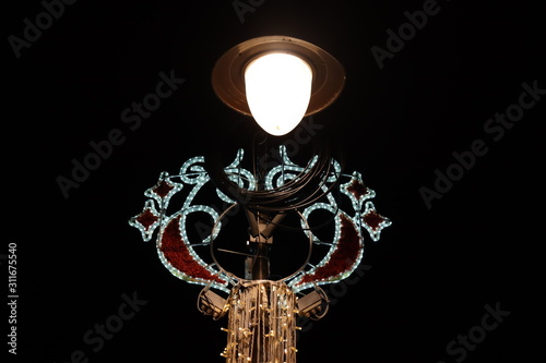 Street lamp with christmas decoration shining in the dark