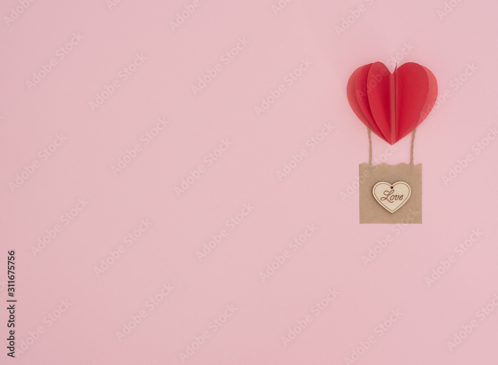 Valentine's Day pink background with red heart balloon with craft basket with wooden heart on it. Valentine greeting card. Flat lay style with copy space. Love, happiness and wedding concept.