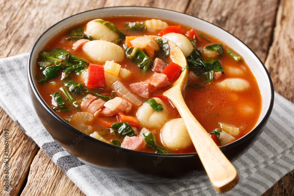 gnocchi soup with sausages,, tomato, spinach and vegetables close-up in a bowl. horizontal