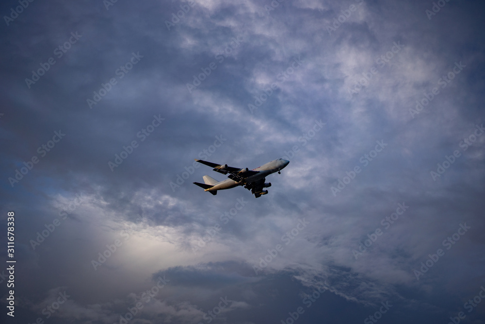 Airplane preparing for landing amongst clouds at sunset