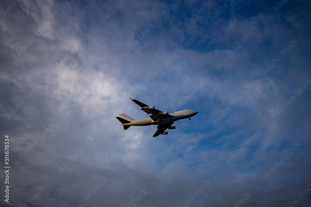 Fototapeta premium Airplane preparing for landing amongst clouds at sunset