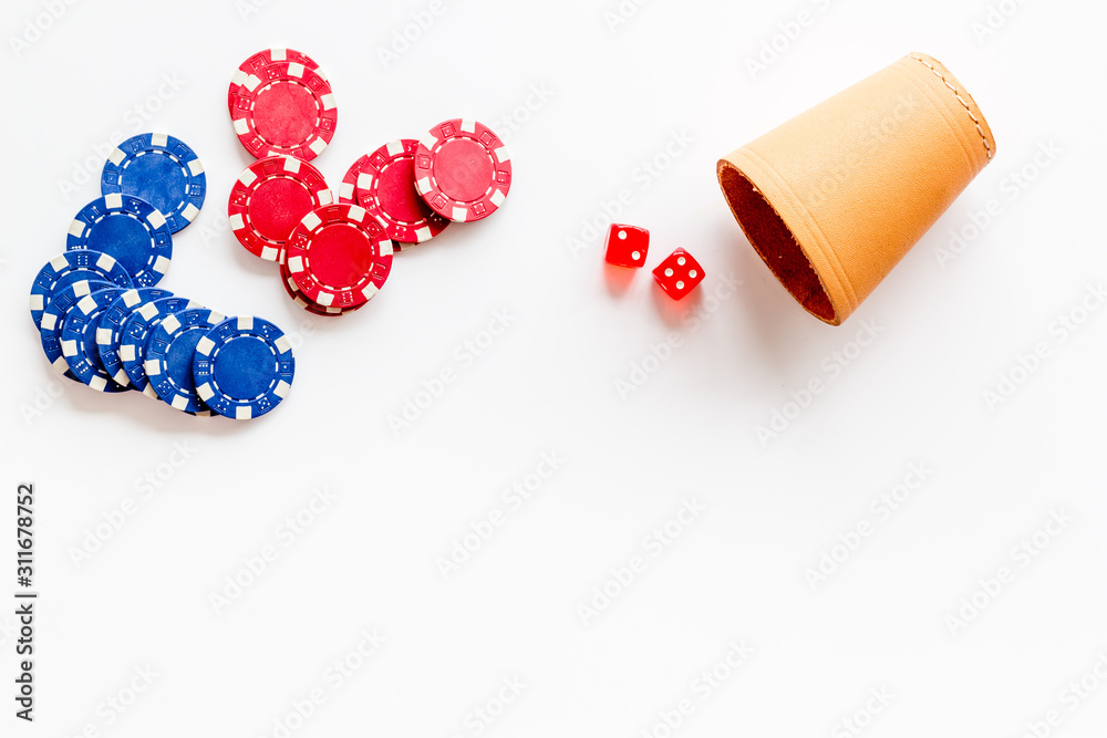 Poker concept. Chips, dices, cup for dice on white background top-down copy space Poker concept. Chips, dices, cup for dice on white background top-down copy space
