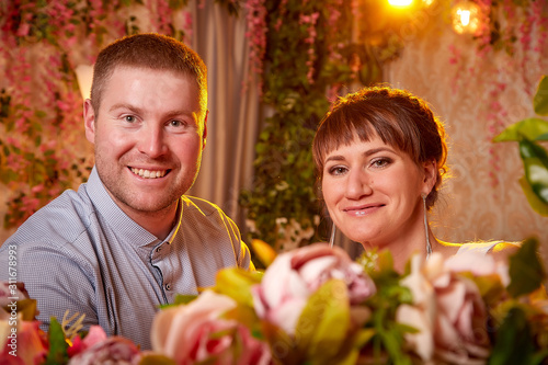 Happy beautiful cute young couple together in nice romantic room full of flowers. Love, celebration, romantic, st. Valentine's day, women day, birthday, date