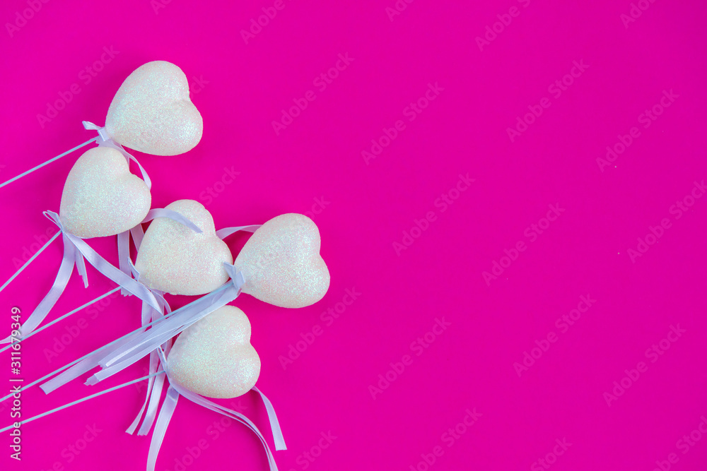 Fototapeta premium White hearts on a stick with a ribbon, pink background. Valentine's Day. Top view, flat lay, copy space