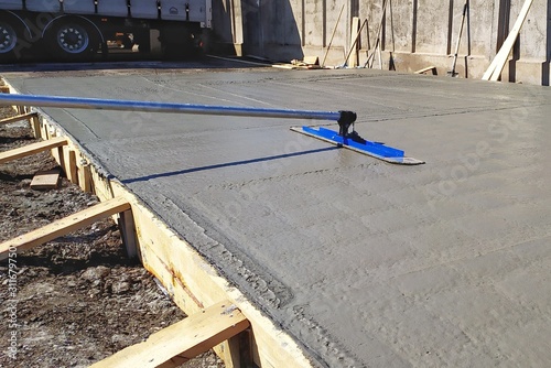 Leveling the concrete floor. Mason building and leveling a first layer of fresh concrete.