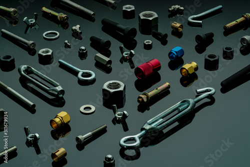 Metal bolts, nuts, and washers. Fasteners equipment. Hardware tools. Different types of nuts, bolts, and screws on table in workshop. Mechanic tools. Threaded fastener use in automotive engineering. photo