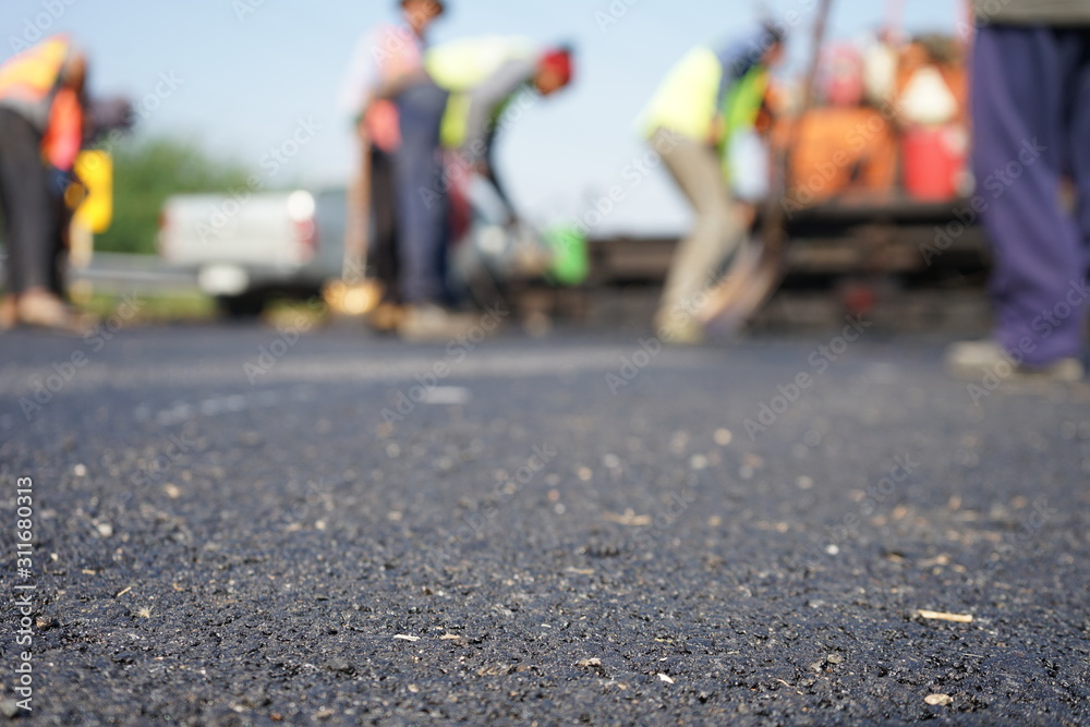 Construction workers on the asphalt road, blurred pictures - obrazy, fototapety, plakaty 