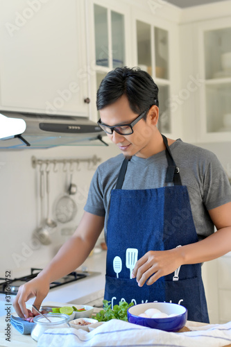 The man in apron standing at kitchen.