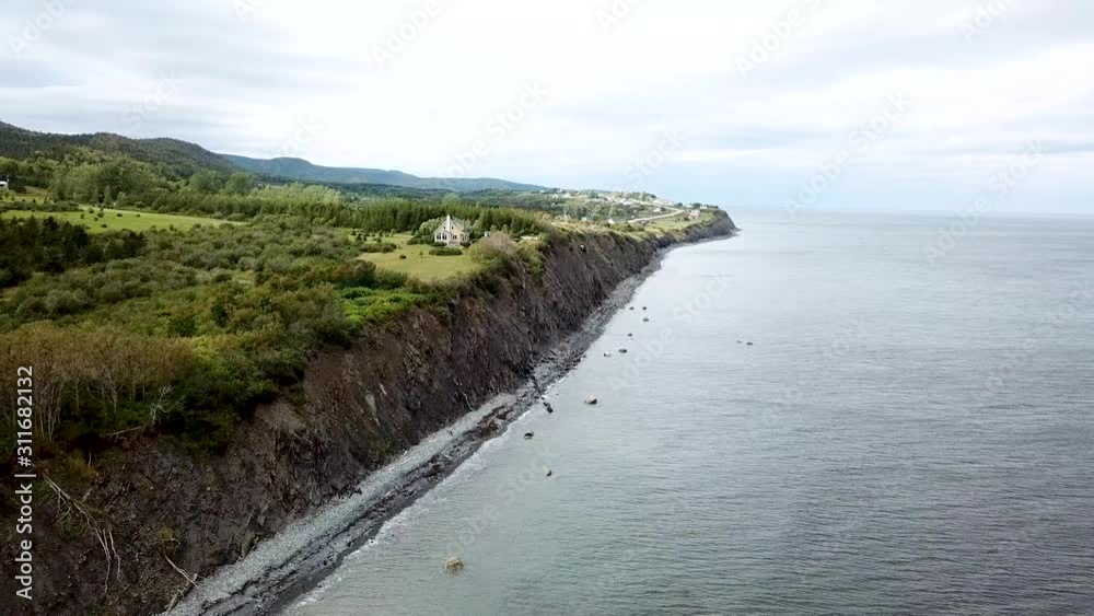 Drone soars along the maritimes coastline of Gaspe, Quebec, Canada. There's a small house overlooking the ocean. Drone soars along the maritimes coastline of Gaspe, Quebec, Canada. There's a small house overlooking the ocean.