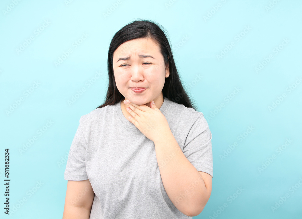 Portrait Asia woman There is a sore throat,on blue background in studio. Portrait Asia woman There is a sore throat,on blue background in studio.