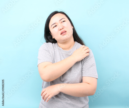 Portrait Asia woman feel very itchy arm, on blue background in studio.