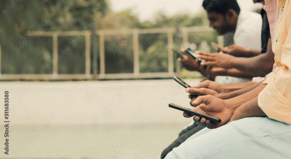 Close up of hands, young people being addicted to devices - Group of friends Sitting in queue using phones at swimming pool - Concept showing of Millennial's busy on smartphones and Technology. 