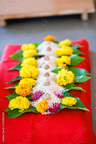 Fototapeta Naklejka Na Ścianę i Meble -  Indian wedding ceremony in Hinduism  : green leaf rice grain and marigold flower decorative on wooden board for bridal entry 