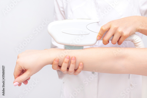 laser hair removal. the girl removes hair with a laser on her arm in a spa salon. the master holds a laser and removes hair.