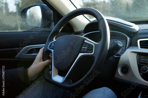male hands hold the wheel of a new car