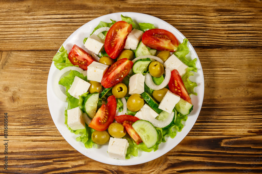 Greek salad with fresh vegetables, feta cheese and green olives on wooden table. Top view