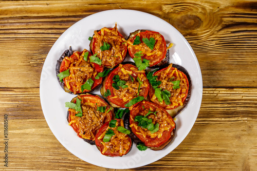 Baked eggplants with tomatoes and cheese on wooden table. Top view