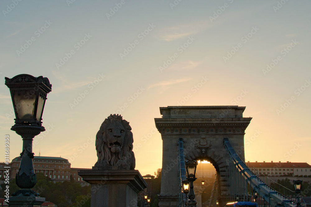 Scenic view of Chain Bridge silhouette during autumn sunset. Beautiful sculpture of Lion and ancient lantern. Romantic and peaceful scene. Panoramic dramatic sunset sky. Budapest, Hungary
