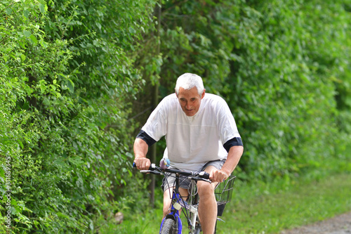 Portrait of  happy man riding a bicycle on green forest road