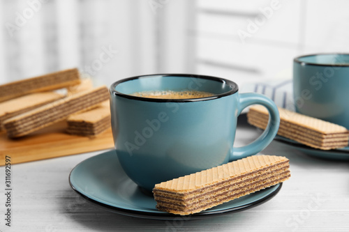 Delicious wafers and coffee for breakfast on white wooden table