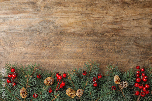 Flat lay composition with fir branches and berries on wooden background, space for text. Winter holidays photo