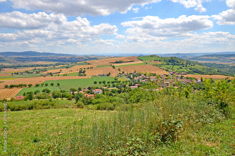 Fototapeta premium Beautiful rural landscape with blue sky, spectacular clouds and wheat fields in Auvergne region in France