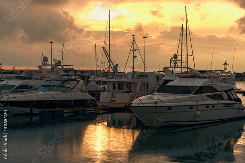 modern small boats and sailboats are parked in a quiet harbor in the seaport of Sochi on a rainy evening