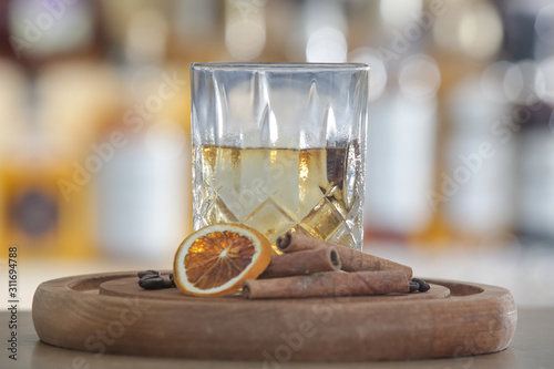 Hazy Whiskey Cocktail  A glass of smoked whiskey served with a slice of dry orange and cinamon stick