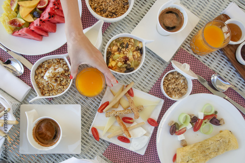 Beautifully arranged breakfast table with coffee, orange juice, pastry, fruits, cereals and eggs, top view