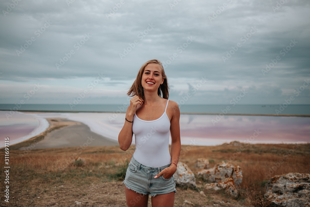 Beautiful girl in a white bodysuit on a background of pink lake Beautiful girl in a white bodysuit on a background of pink lake