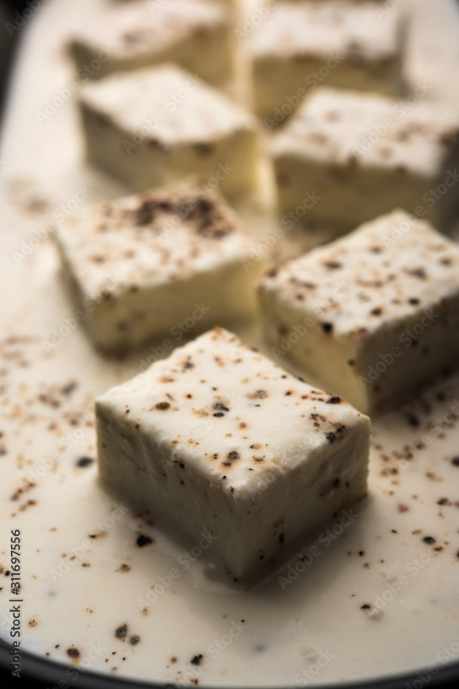 Paneer Dum Kali Mirch / Kalimirch, prepared in a white creamy gravy and black pepper powder sprinkled over it. served in a bowl. Selective focus