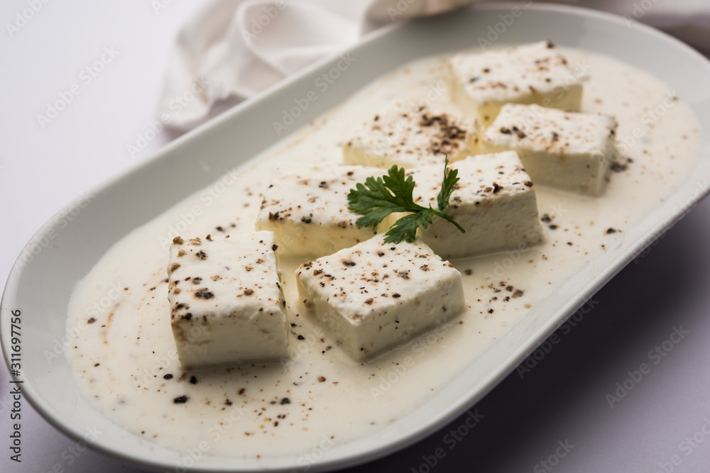 Paneer Dum Kali Mirch / Kalimirch, prepared in a white creamy gravy and black pepper powder sprinkled over it. served in a bowl. Selective focus