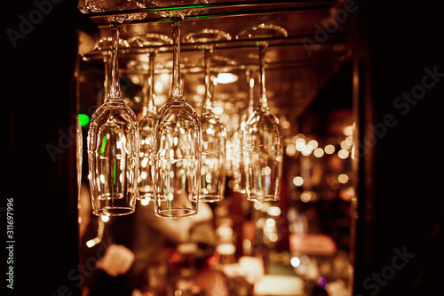 Glasses of wine. Glasses hanging above the bar in the restaurant. Empty glasses for wine. Wine and martini glasses in shelf above a bar rack in restaurant. blue lights, blue background, night life