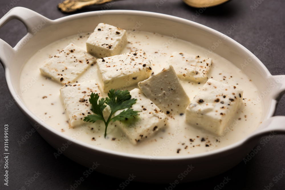Paneer Dum Kali Mirch / Kalimirch, prepared in a white creamy gravy and black pepper powder sprinkled over it. served in a bowl. Selective focus