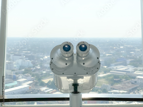 binoculars for tourist inside the building and city background.