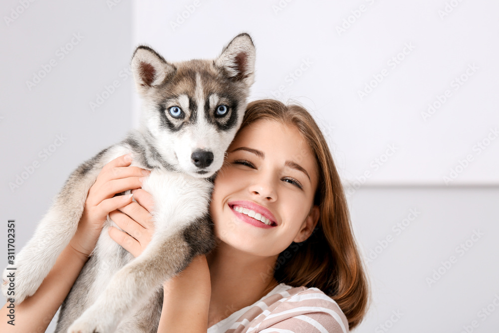 Cute teenage girl with funny husky puppy at home