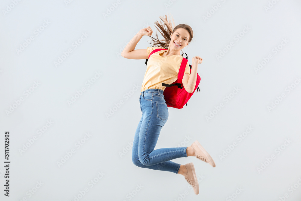 Jumping female student against light background - obrazy, fototapety, plakaty 