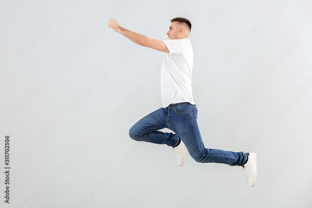 Jumping young man against light background