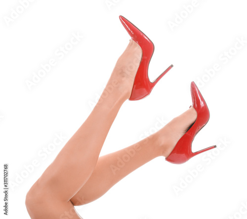 Legs of young woman in high-heeled shoes on white background