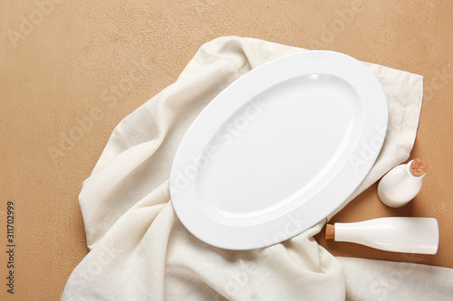 Empty plate and napkin on color background