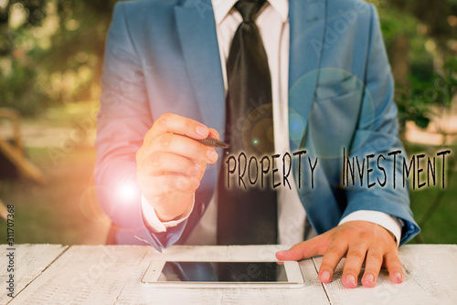 Text sign showing Property Investment. Business photo text Asset purchased and held primarily for its future income Businessman holds pen and points into copy space © Artur