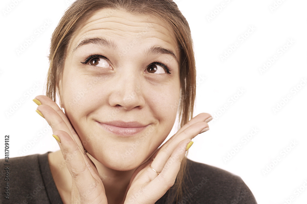 The young beautiful girl smiles and holds hands near the face. The young beautiful girl smiles and holds hands near the face.