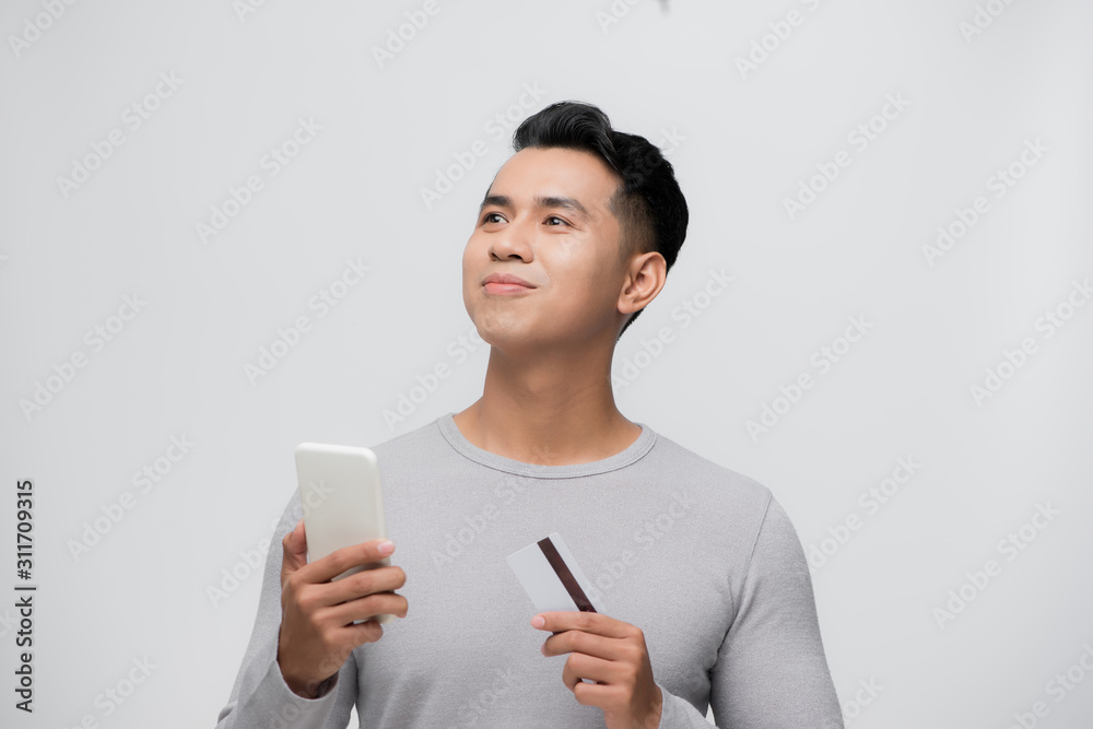Handsome smiling young Asian man showing credit card for mobile payment concept Handsome smiling young Asian man showing credit card for mobile payment concept