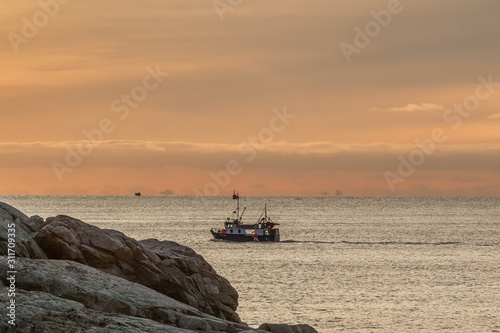 fishing boat with amazing sunset in background in lofoten, norway.