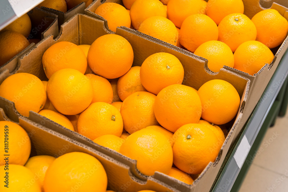 ripe juicy oranges in boxes on the counter in the store, citrus